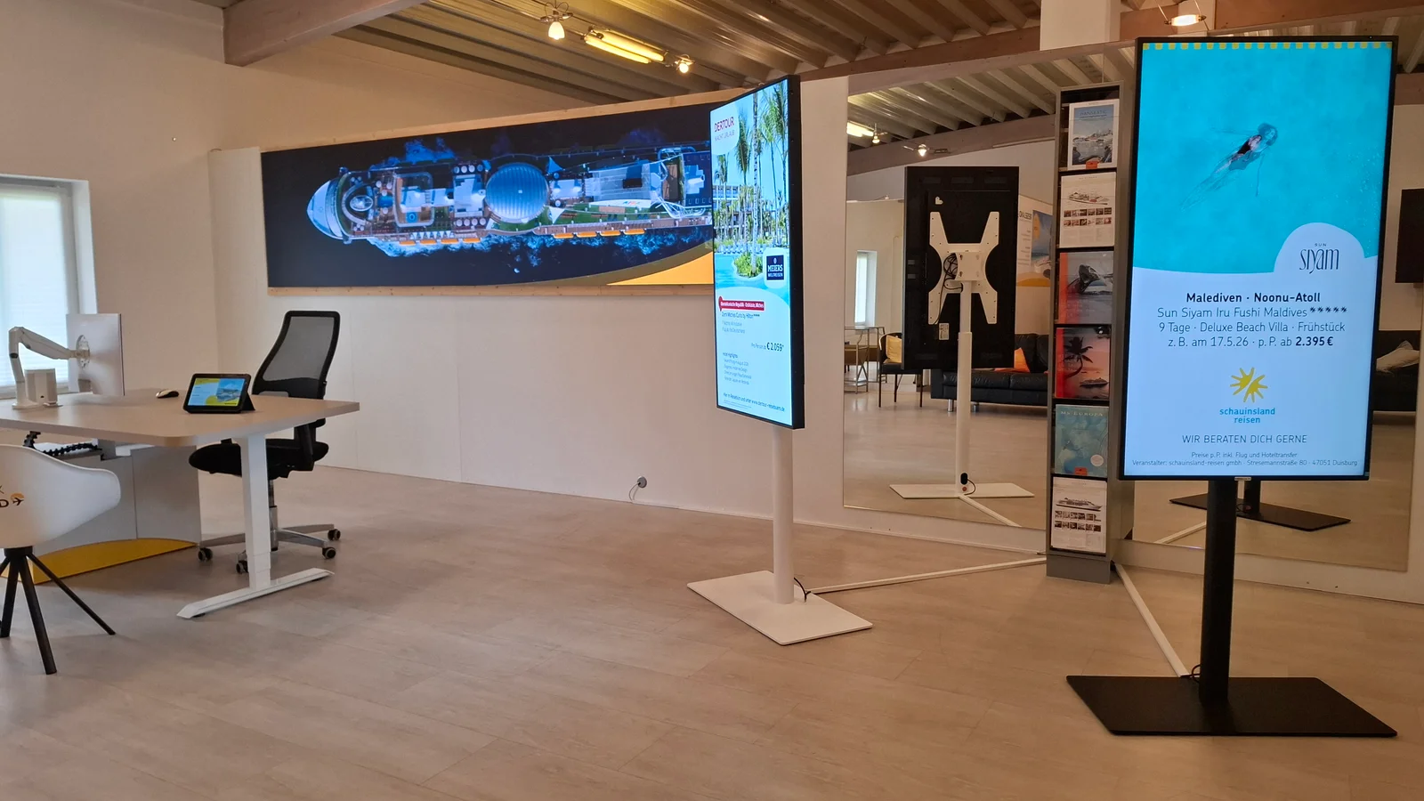 LED-Wand und freistehende Hochformat-Displays mit Reisemotiven im Kermax-Showroom